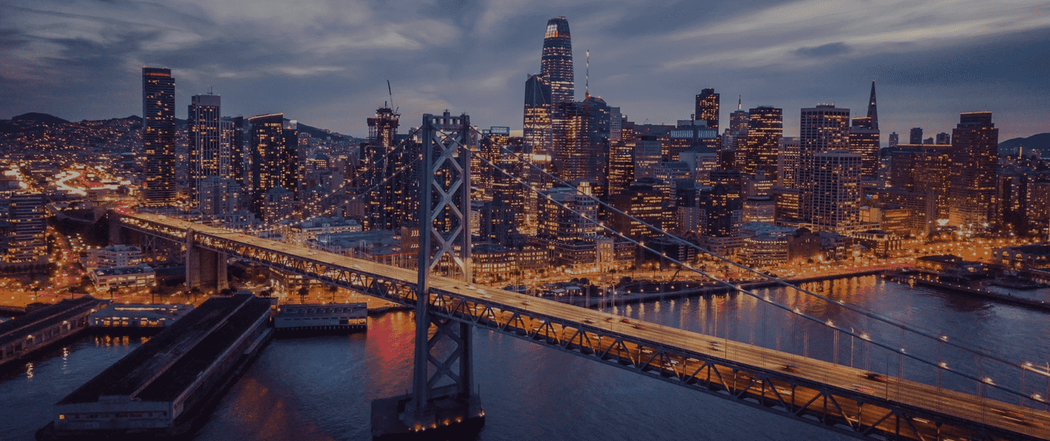 A city skyline with lights and a bridge.