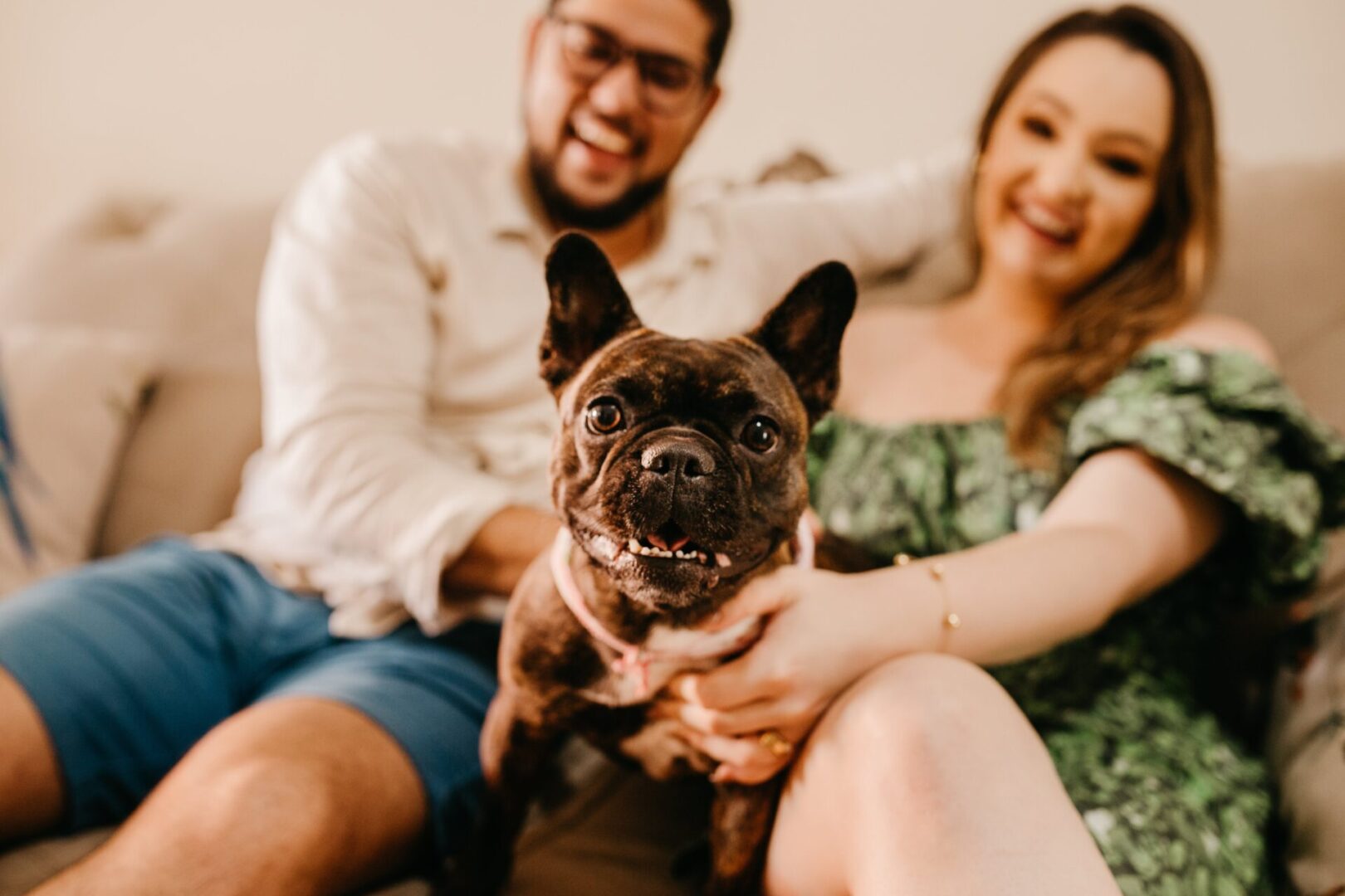 A man and woman sitting on the couch with their dog.